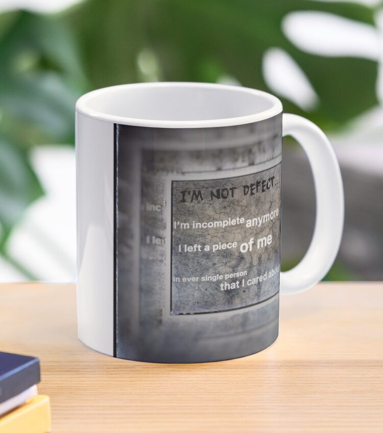 White mug featuring a motivational quote on a textured grey background.